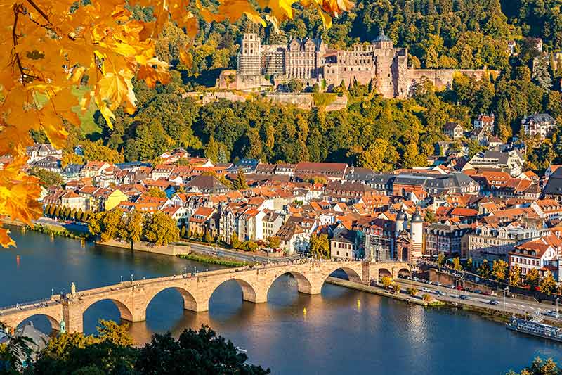Heidelberg Castle on the hill behind the town and the river in autumn