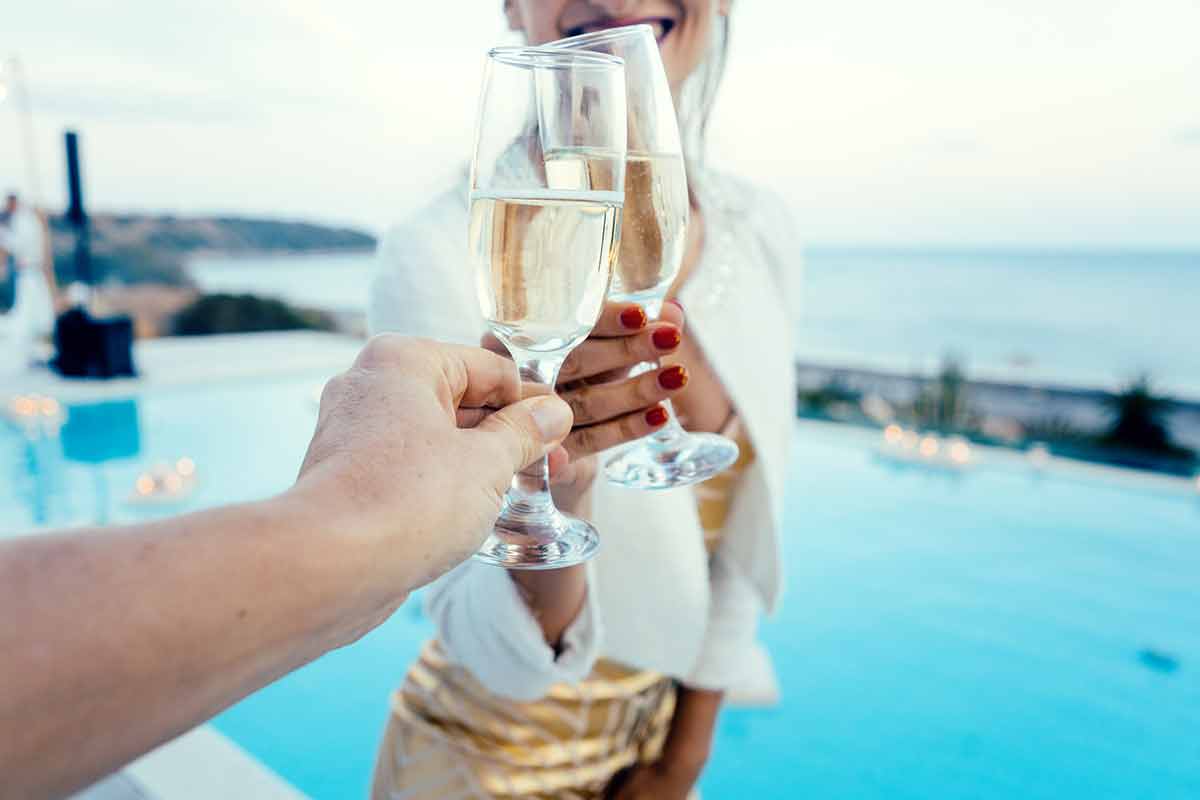 Woman and man clinking glasses at pool party