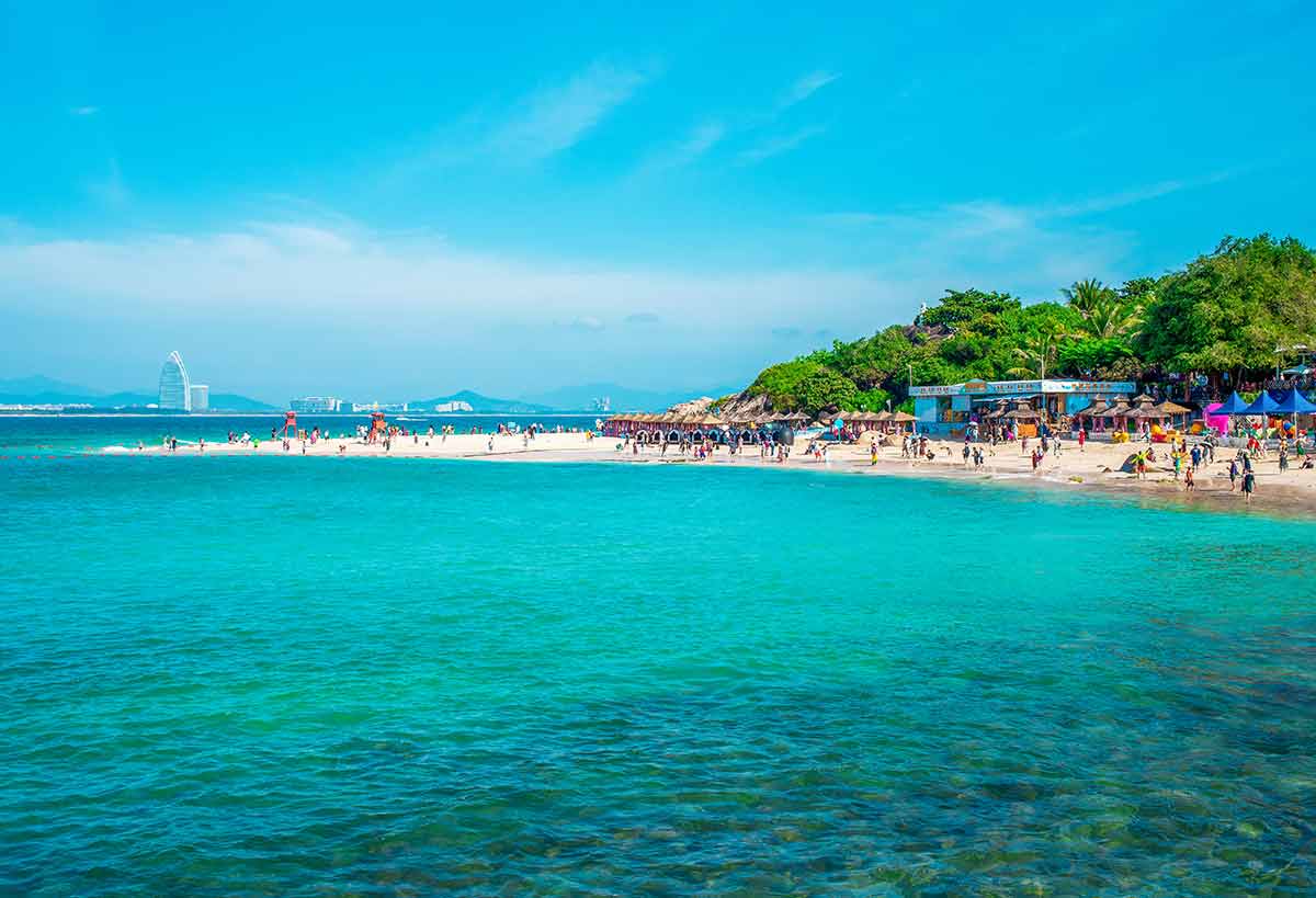best beaches china (Wuzhizhou Island) a crowd on the beach with lush backdrop