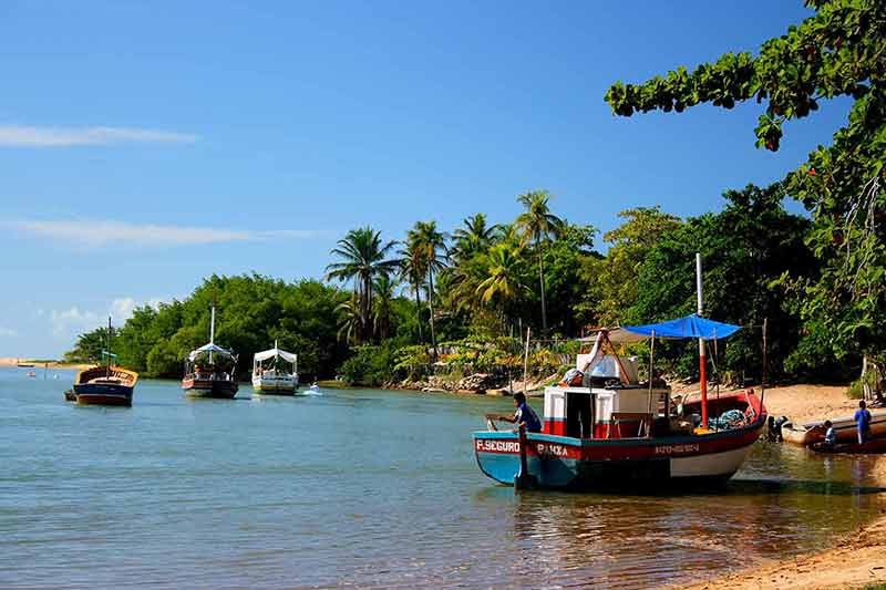 best beaches in brazil fishing boats moored near the beach with lush jungle at one end of the shore
