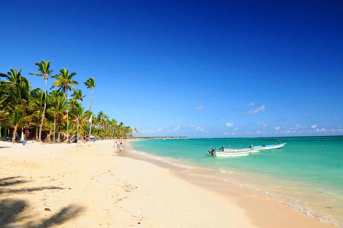 best beaches in dominican republic sand, a boat on emerald water and palm trees