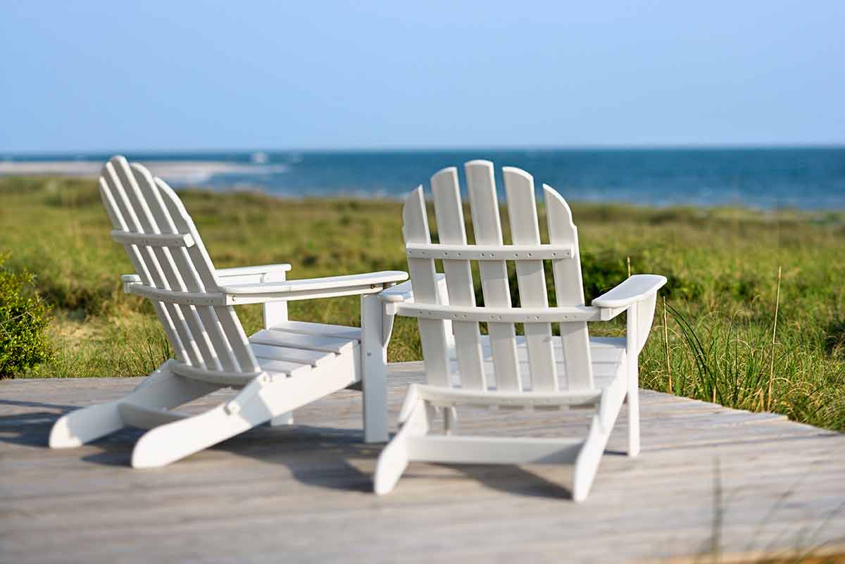 best beaches in north carolina for families Adirondack chairs on a deck looking towards the beach on Bald Head Island