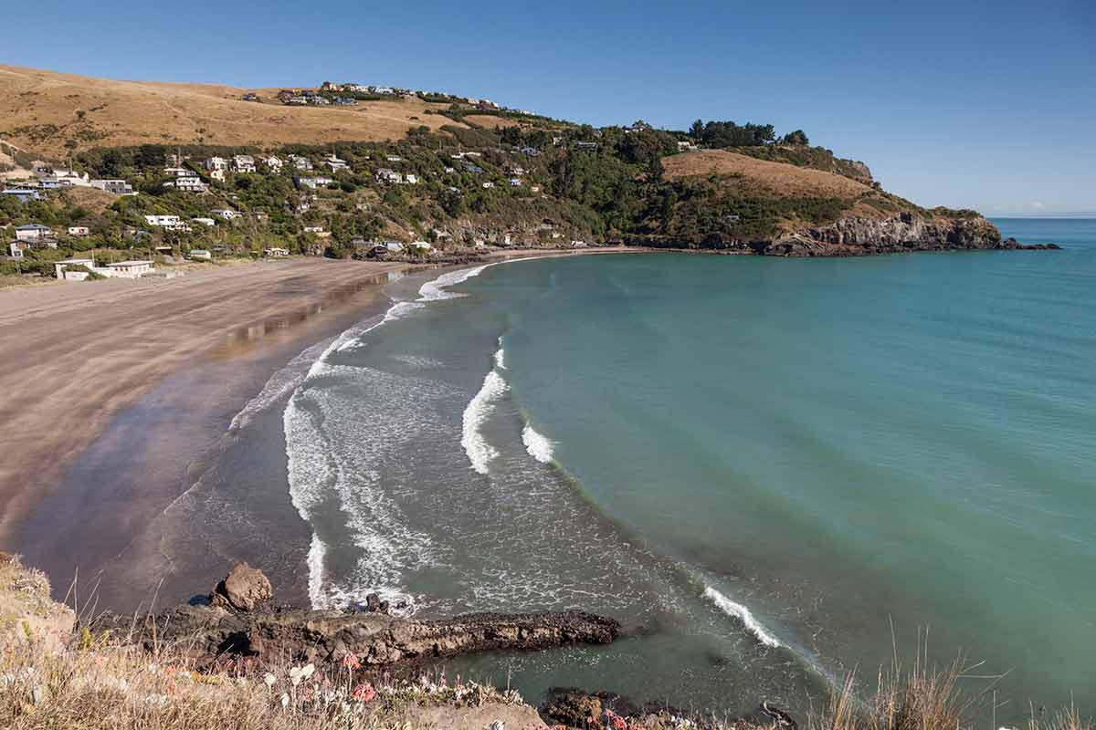 best beaches in south island new zealand (taylor's mistake beach with houses on the hill in the background