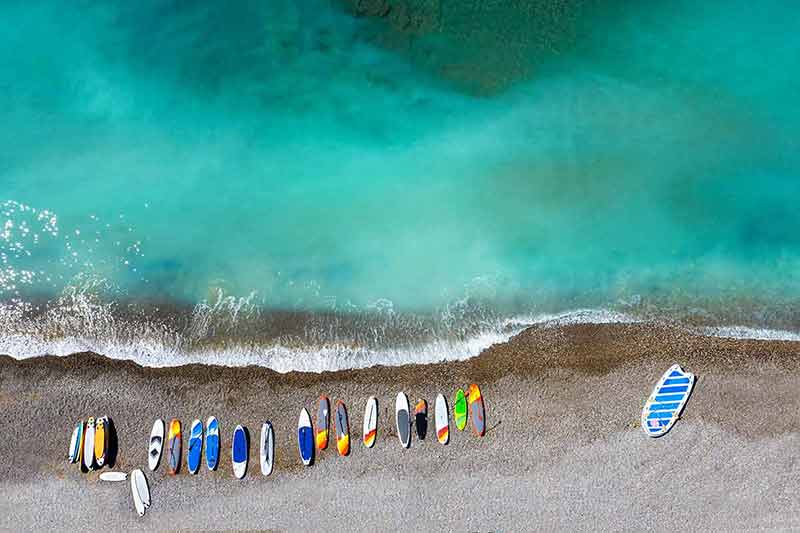 best beaches in south of france colourful surfboards lying chaotically on a shingle beach in France.