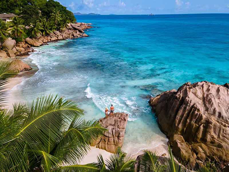 best beaches in the seychelles couple standing on a rock admiring the ocean