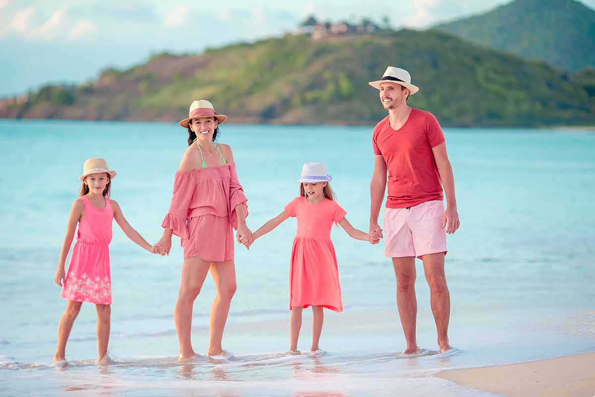 Happy Family With Kids Walk On The Beach At Sunset