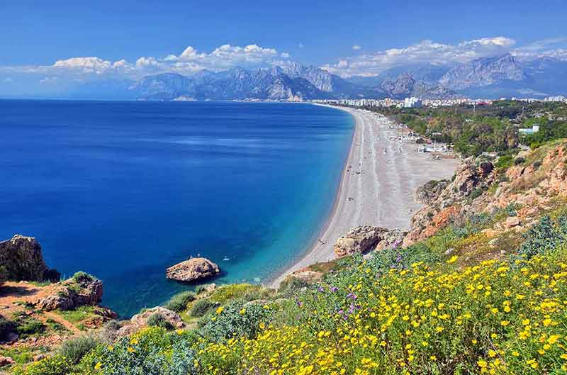 best beaches in turkey for families aerial view of Konyaalti beach with yellow flowers in the foreground