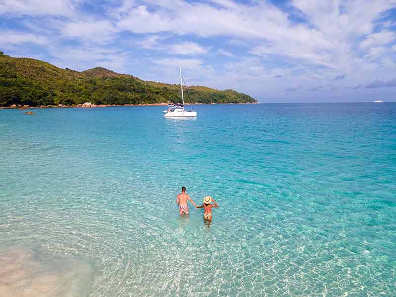 best beaches seychelles man and woman holding hands in the clear water