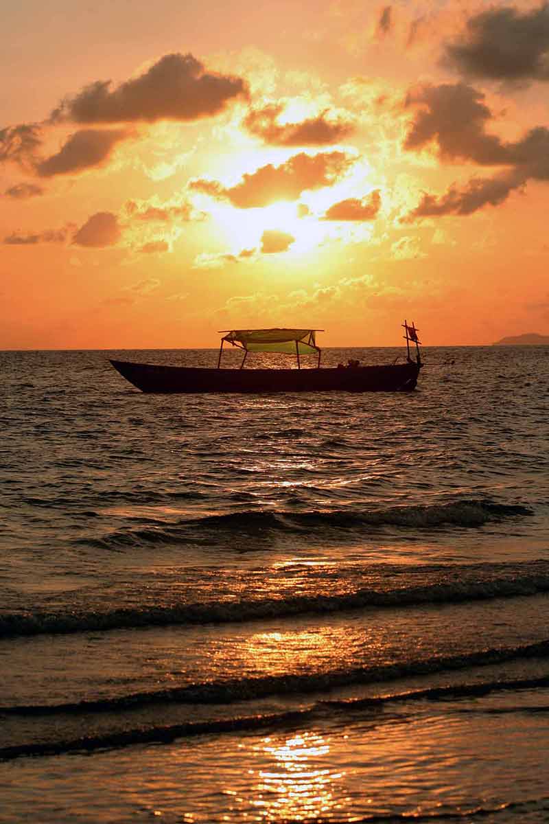 best cambodia beaches vertical shot of a boat moored near the beach and orange sunset