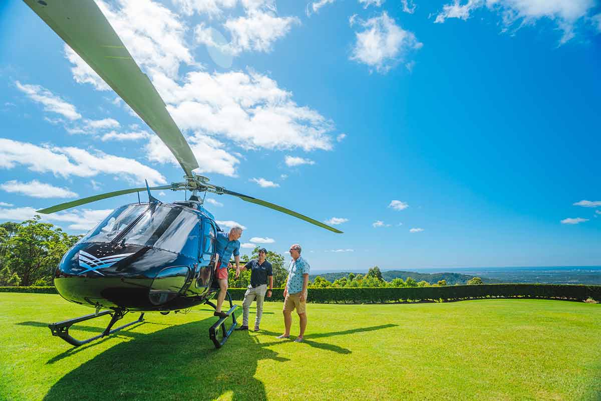 best day trips from brisbane three men getting out of a helicopter