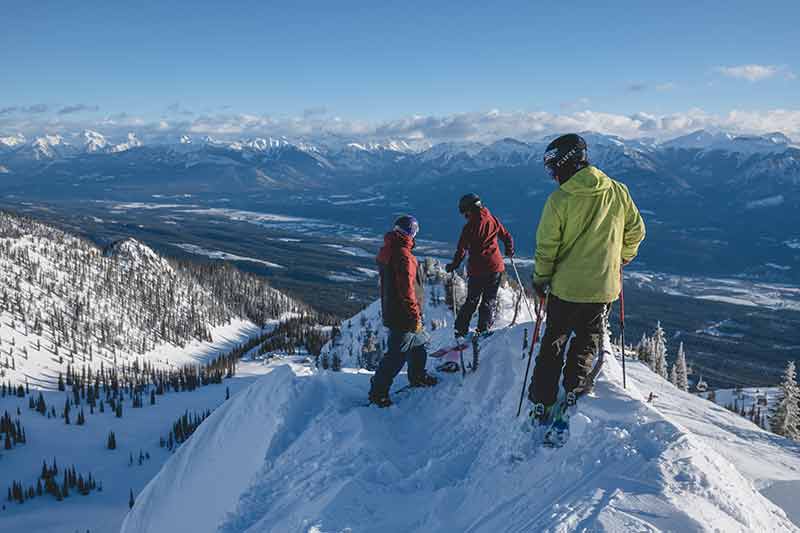 three skiers admiring the view at one of the best family ski resorts in canada if you're on a budget