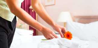 housekeeping placing a flower on a bed