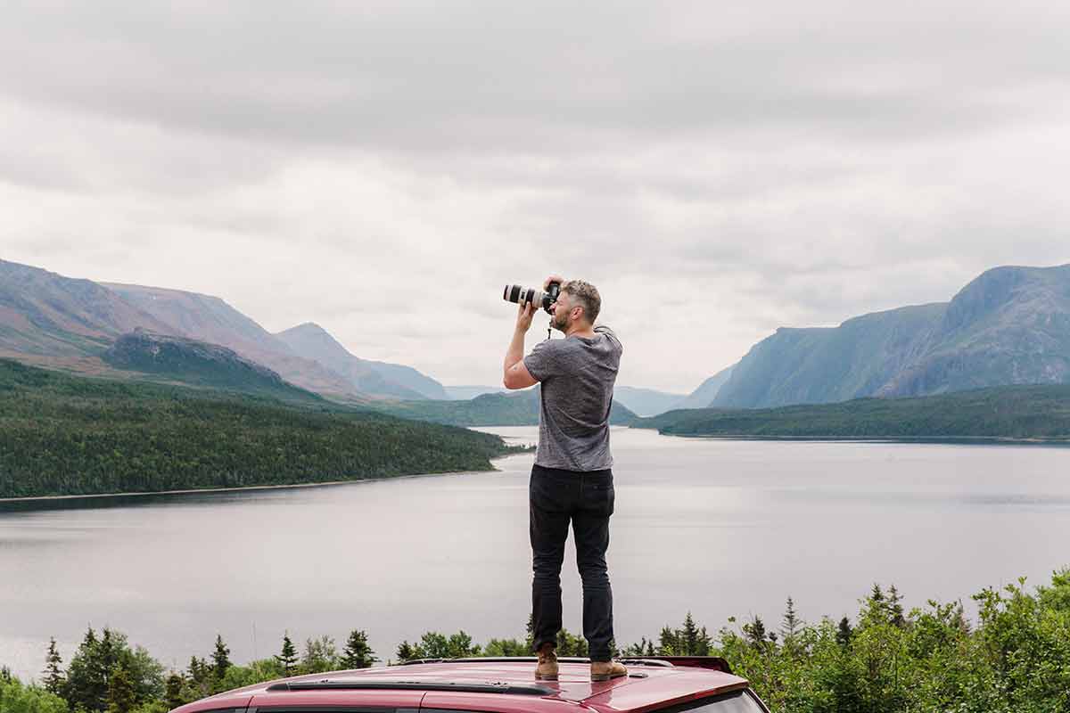 photographer on the roof of his car in one of the best national parks in canada