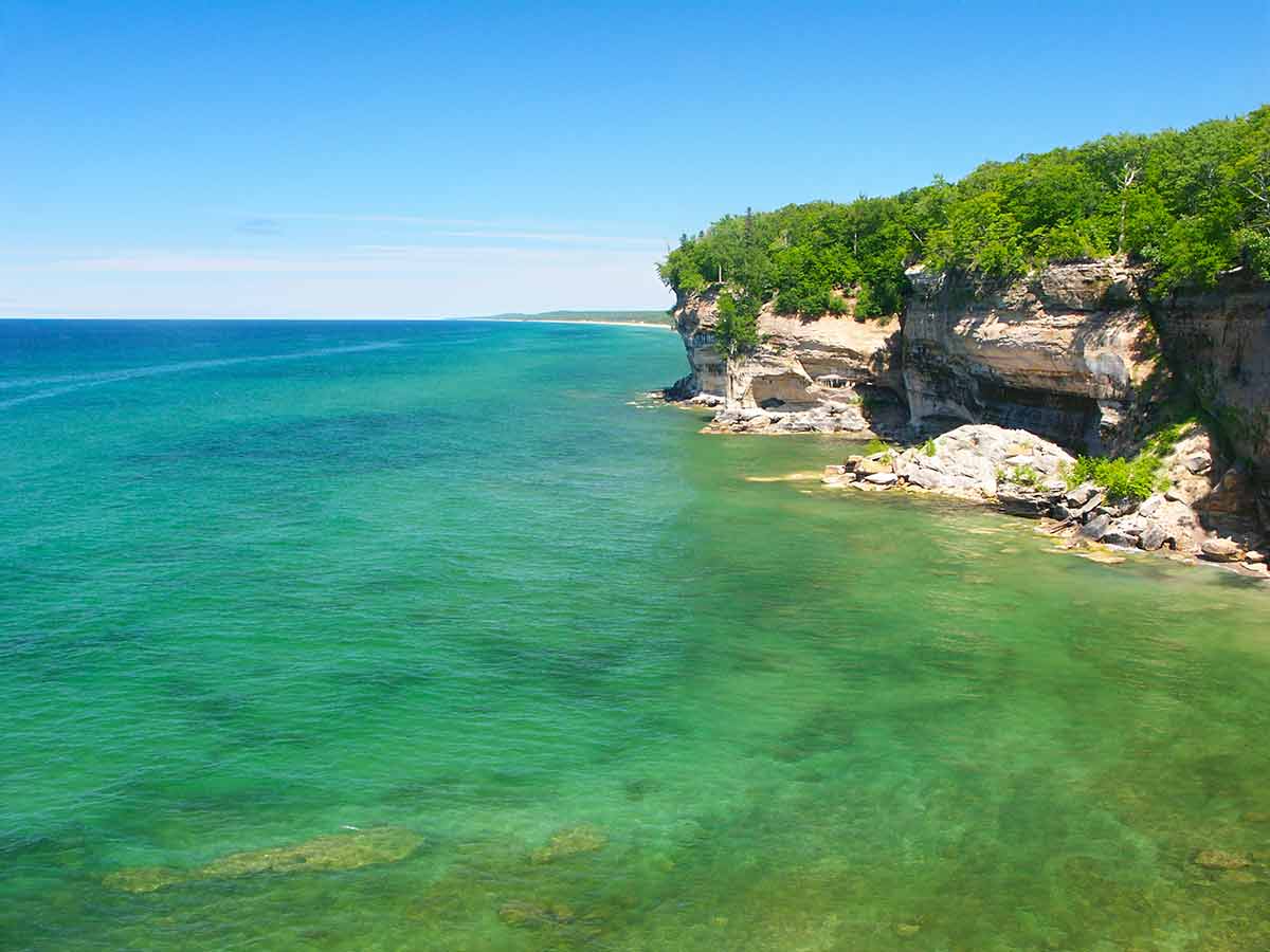 best national parks in michigan clear emeral water and rocky cliffs with green trees