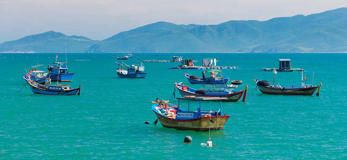 Vietnam coastline with fishing boats in the water near the best secluded beaches in vietnam