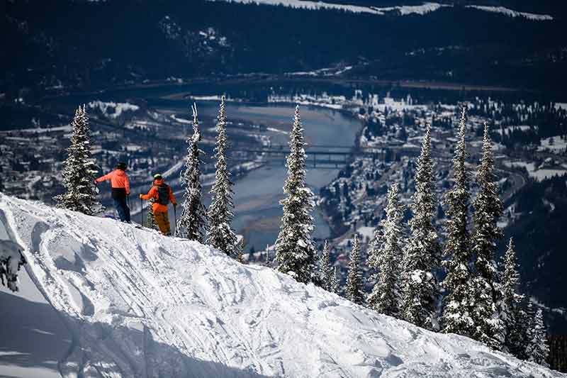 two skiers gazing at Revelstoke town from one of the best ski resorts in bc canada