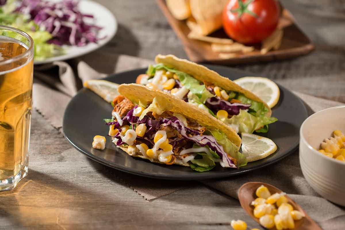 Traditional mexican taco with chicken and vegetables on wooden table.