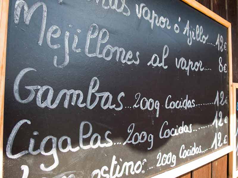 best things to do in ibiza Black placards Spanish handwritten in the brown wood wall with typical menu food dishes in Spain restaurant
