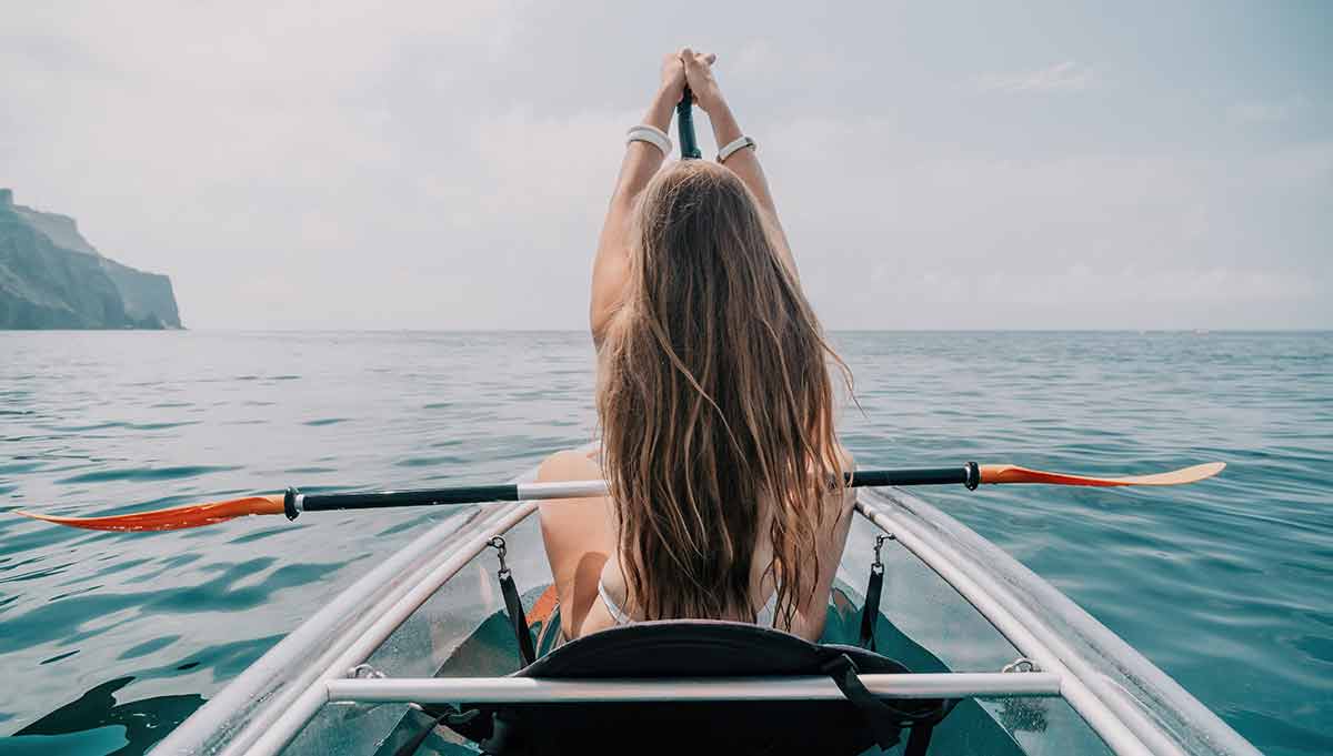 Happy Young Woman With Long Hair Floating In Transparent Kayak On The Crystal Clear Sea
