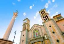 best things to do in tijuana A view of the exterior of the cathedral, the arch, two towers, columns, clock and cross.