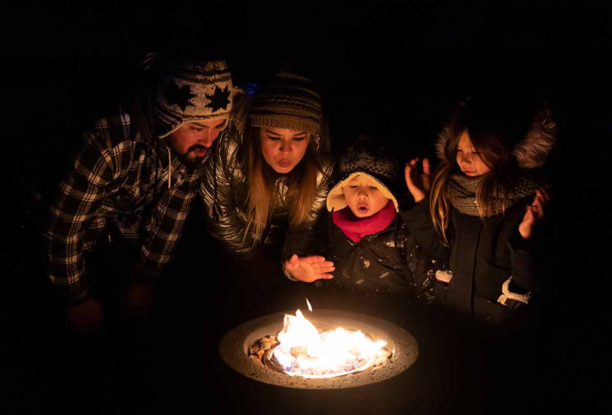 best things to do in toronto at night A family warms up at a fire pit warming station while visiting the Toronto Zoo in winter.