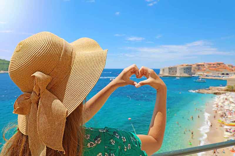 best time to visit dubrovnik croatia Young beautiful woman in Dubrovnik making hands shaped heart on spring summer warm sunny day. Girl with hat happy outdoors in her travel in Southern Croatia, Europe.