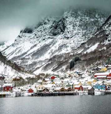 best time to visit fjords norway snow-covered village and mountain backdrop