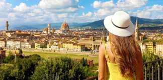best time to visit florence italy Woman in yellow dress and hat looks at stunning panoramic view of Florence, Italy.