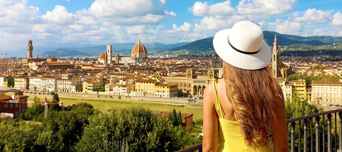 best time to visit florence italy Woman in yellow dress and hat looks at stunning panoramic view of Florence, Italy.