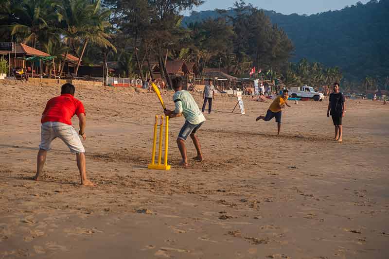 best time to visit goa india Indian adults playing cricket on beach