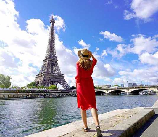 best time to visit paris france Back view of young woman visiting the city of Paris with Eiffel Tower and Seine River.