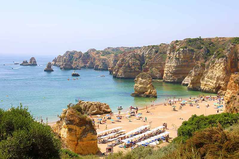 best time to visit portugal beaches people sunbathing and enjoying on the beach near Lagos
