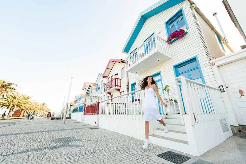 best time to visit portugal girl in white dress walking out of a cottage