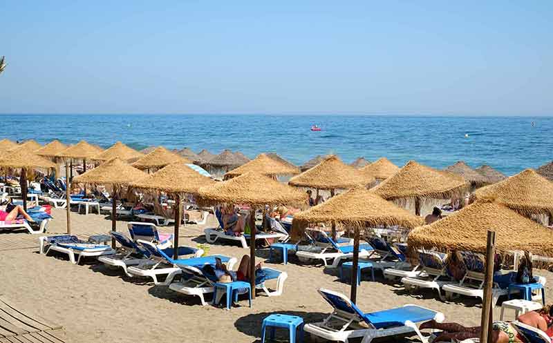best time to visit spain 2022 rows of thatched umbrellas and lounges by the sea