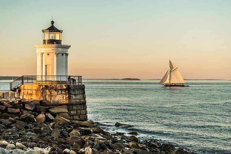 South Portland Bug Lighthouse at sunset with sailing boat in the background