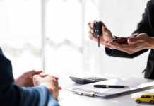 hand handing over key with car rental contract on the table