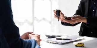 hand handing over key with car rental contract on the table