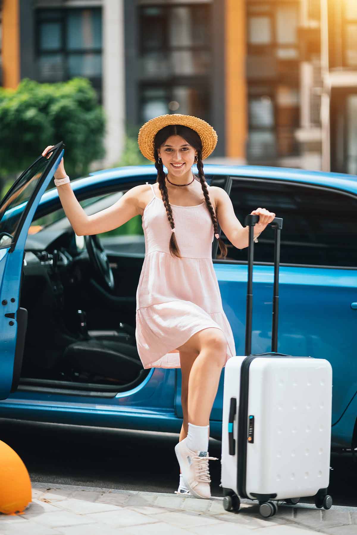 girl with a roller suitcase wearing a straw hat