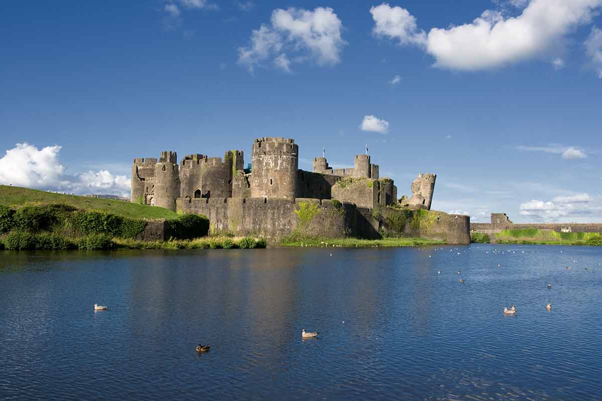 castles in south wales Caerphilly Castle with water in the foreground and blue sky