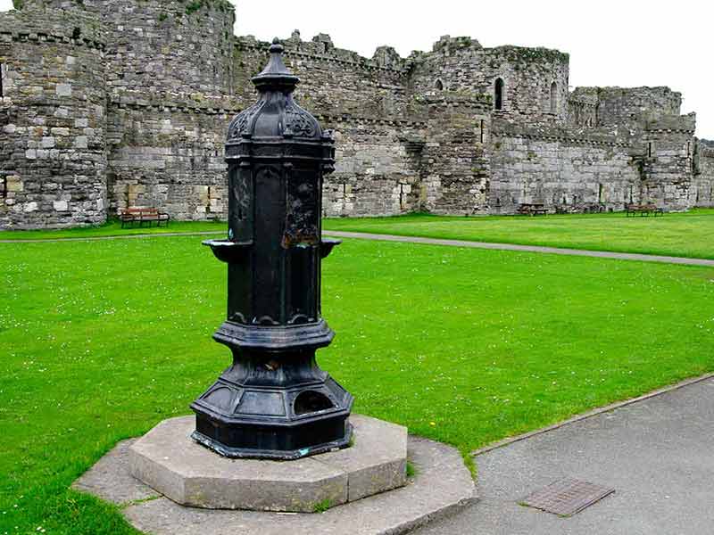 castles to visit in wales Beaumaris Castle garden black ornament and castle wall in the background.