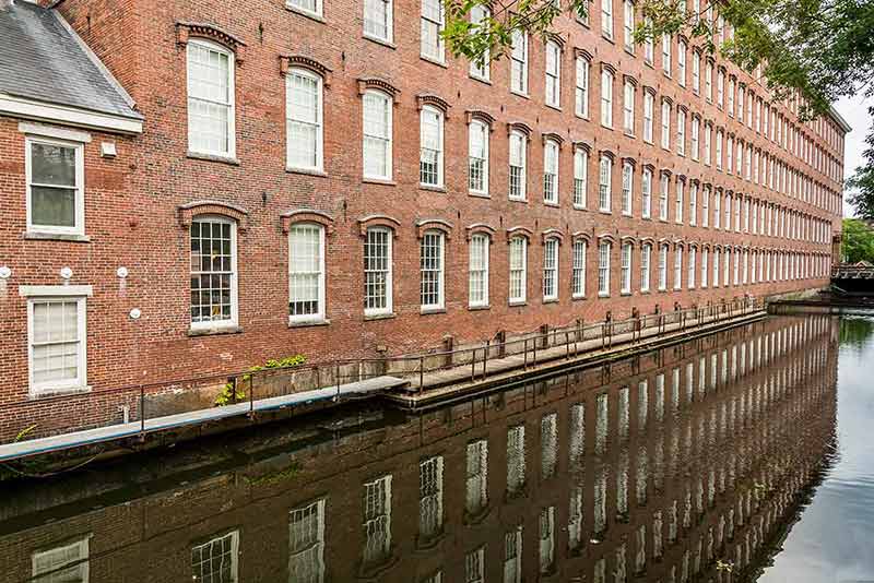 Boott Cotton Mills' brown brick building reflected in a canal