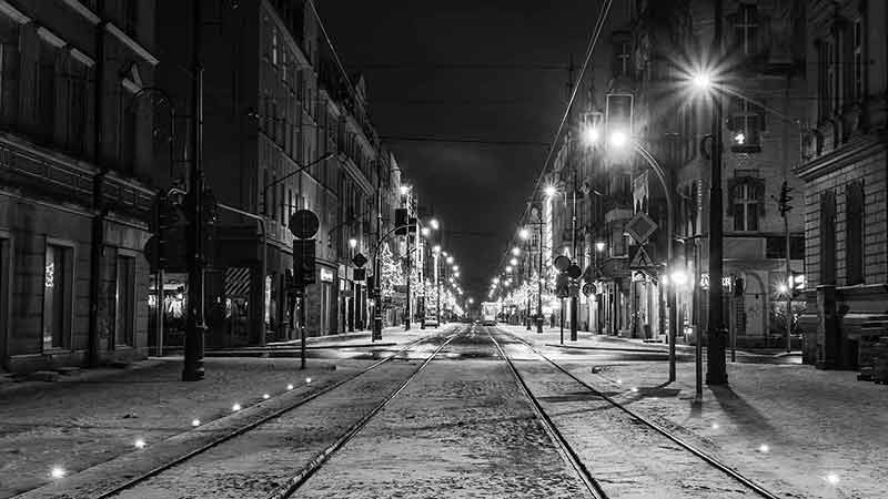 cities in poland black and white photo of city with tram tracks