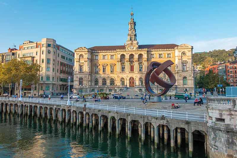 cities in spain to visit historic building and modern sculpture by the river