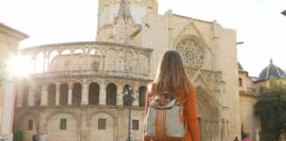 cities to visit in spain back view of beautiful girl visiting Valencia Cathedral on sunny day