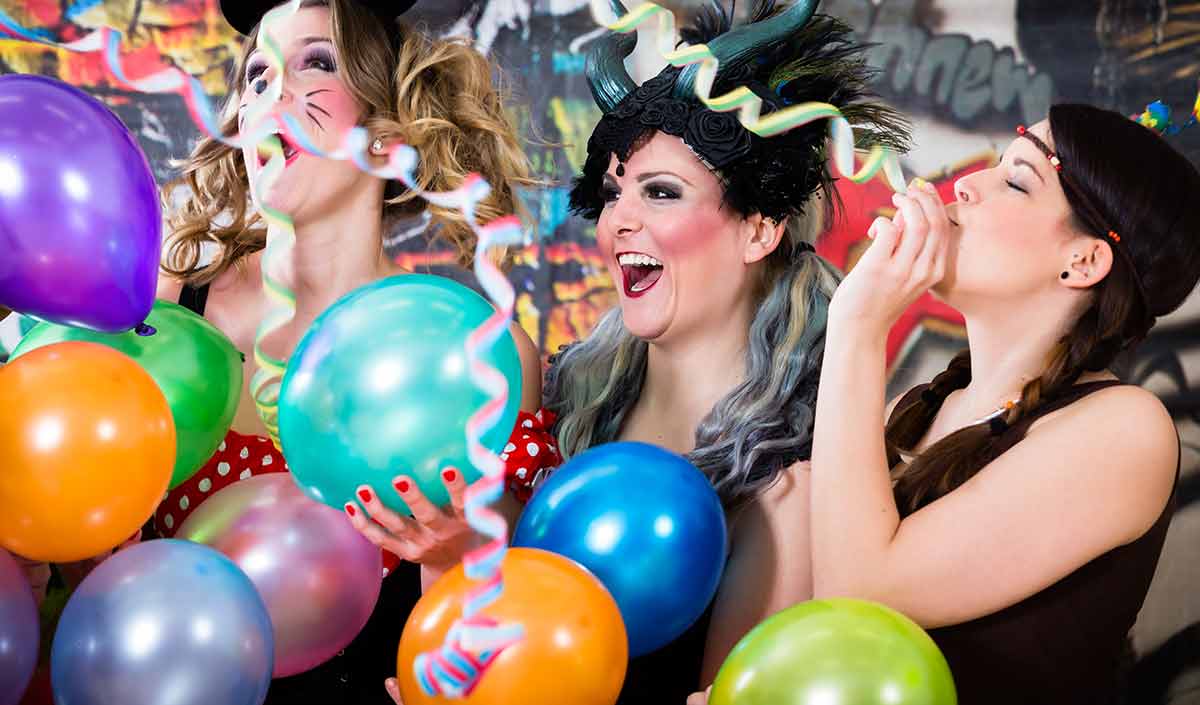three women with balloons and party hats