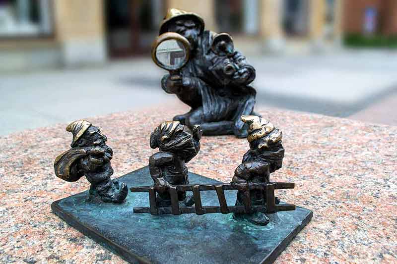 Dwarf gnomes sculpture with magnifying glass
