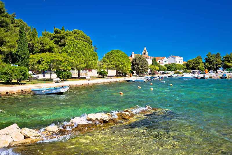 croatia beaches clear water, green trees and historic buildings in the background