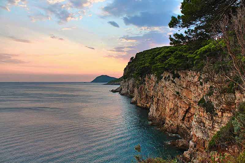 croatia best beaches time to visit Cliff face with the sea and a beautiful sunset with birds flying in the sky