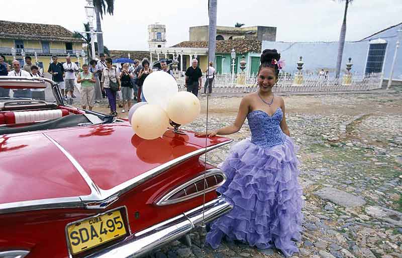 cuba best time of year to visit a vintage red car and woman in a party frock