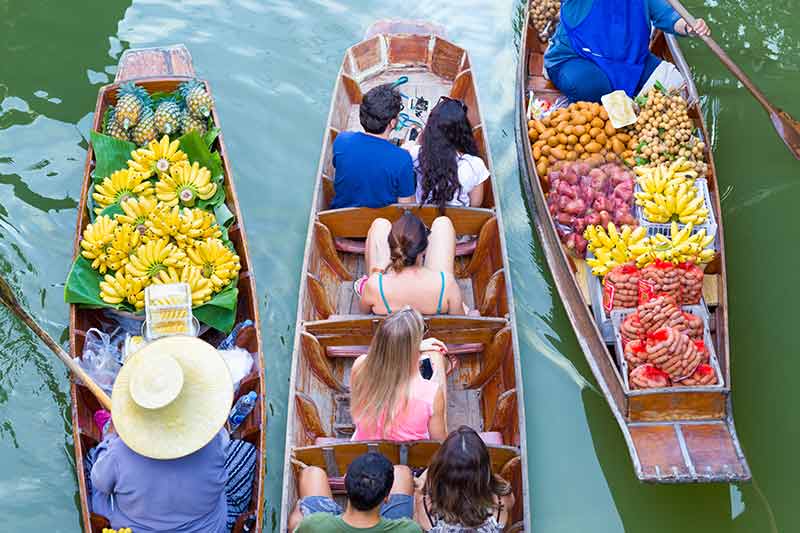 aerial view of three boats with tourists and fruit vendors